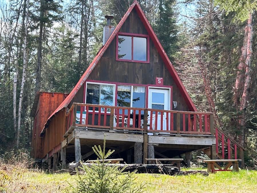Front view of cabin number 5 with its wooden deck located in the forest.