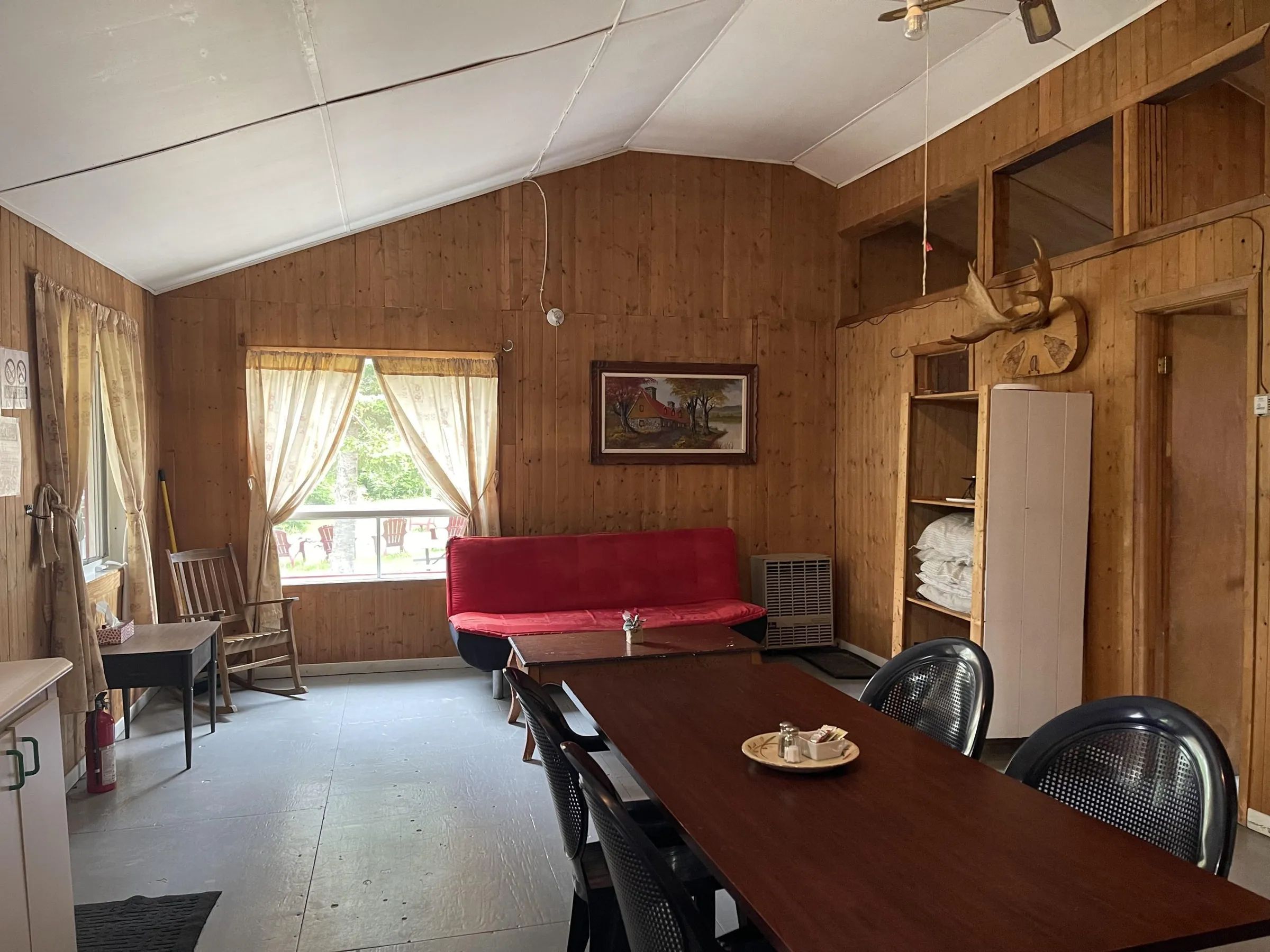 The dining area and living room share a cozy open space with wooden walls.
