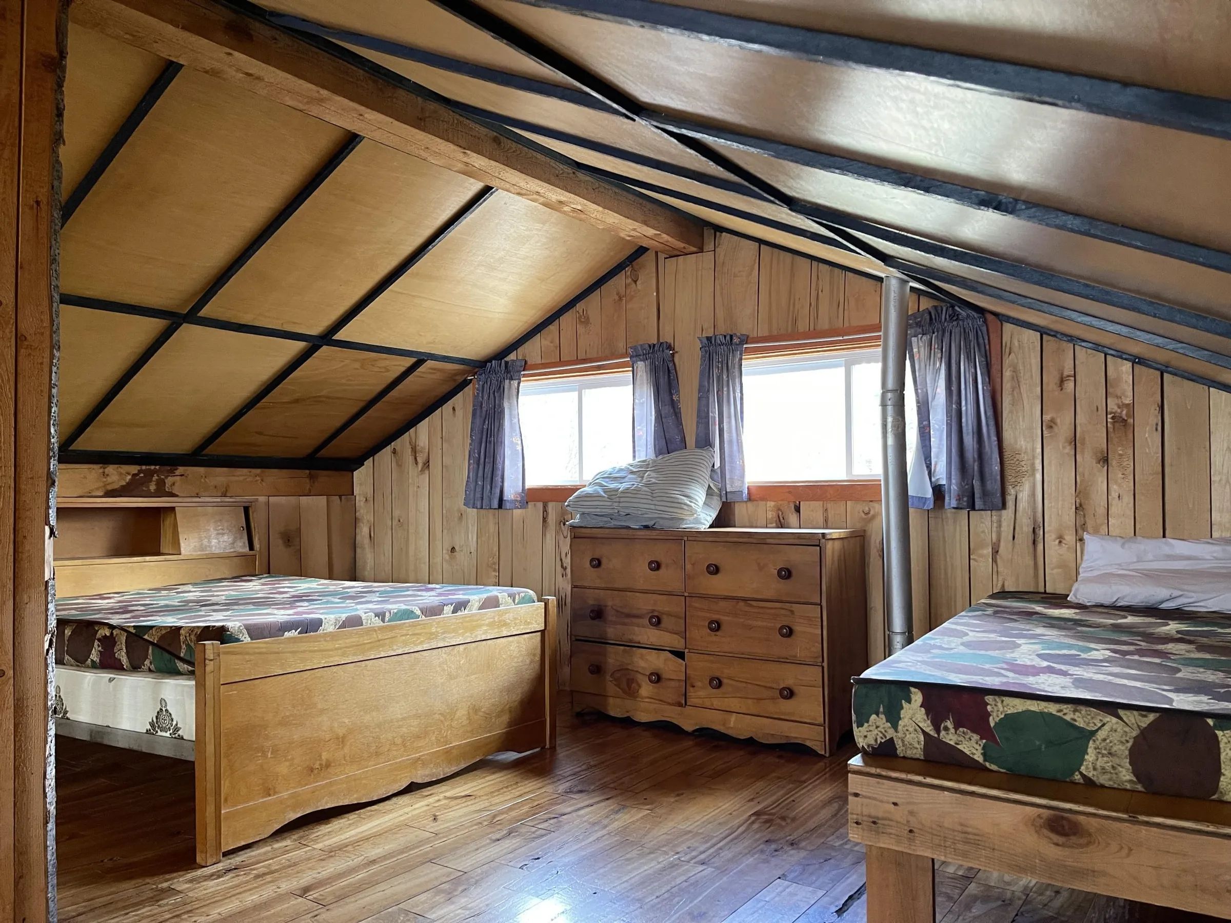 Cette chambre rustique est équipée de deux lits en bois et d'une commode.