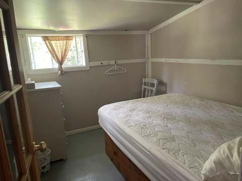Cette chambre lumineuse du chalet 5 comprend un lit double avec matelas ainsi qu'une commode.