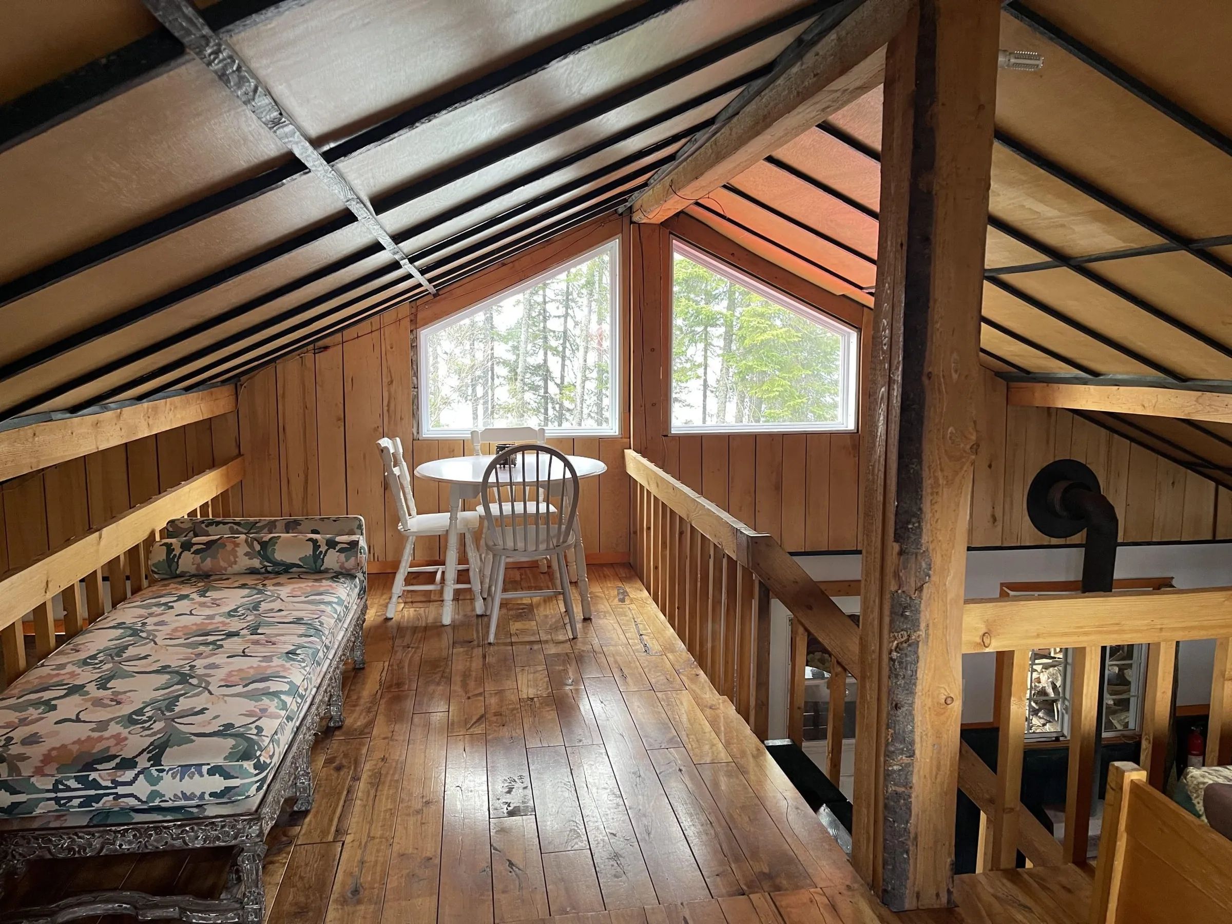 La mezzanine du chalet dispose d'un coin détente et d'une petite table avec vue sur la forêt.