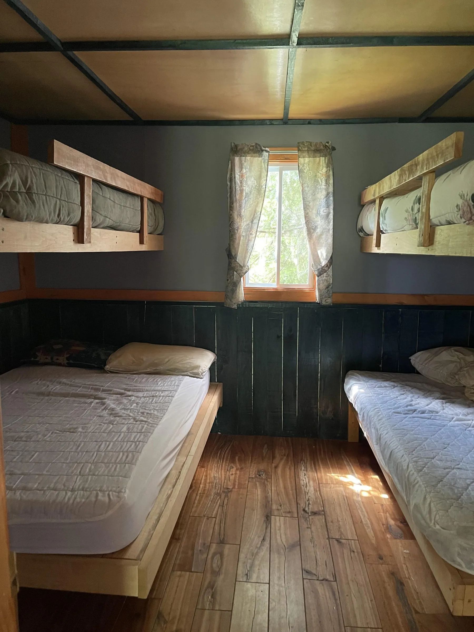 Cette chambre du chalet 7 dispose de deux lits simples et de deux lits superposés en bois.