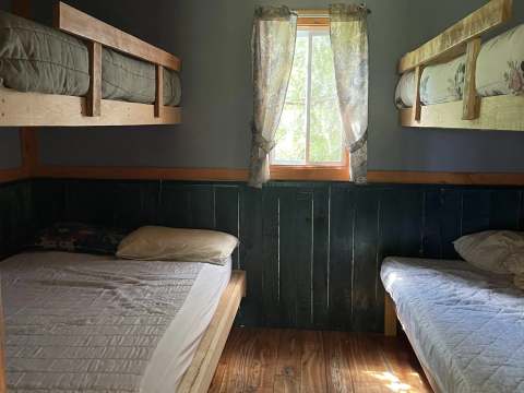 Cette chambre du chalet 7 dispose de deux lits simples et de deux lits superposés en bois.