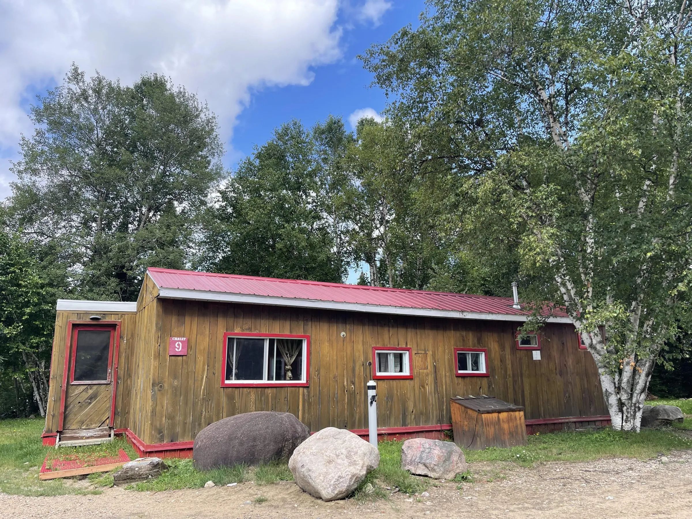 Exterior view of cabin 9 with its wooden siding and red roof.