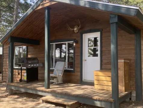 Exterior view of cabin 2 with its covered deck, barbecue, and outdoor seating.