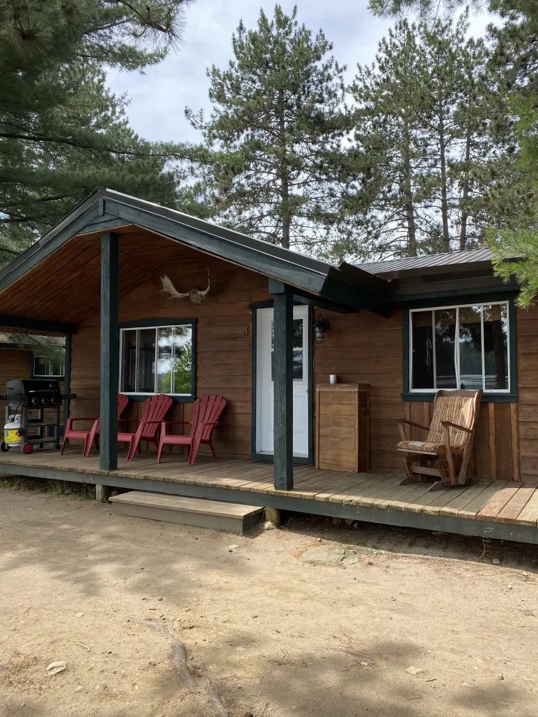 Vue de l'extérieur du chalet numéro 3 avec sa galerie couverte et ses chaises de détente.