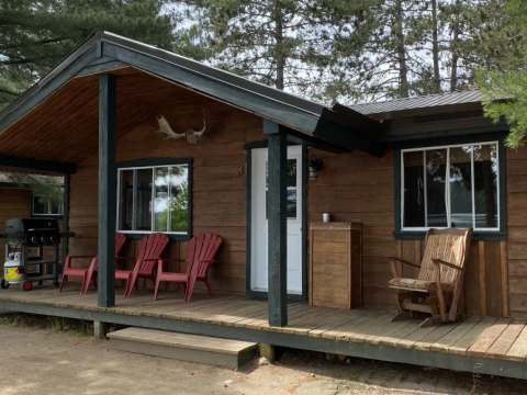 Vue de l'extérieur du chalet numéro 3 avec sa galerie couverte et ses chaises de détente.