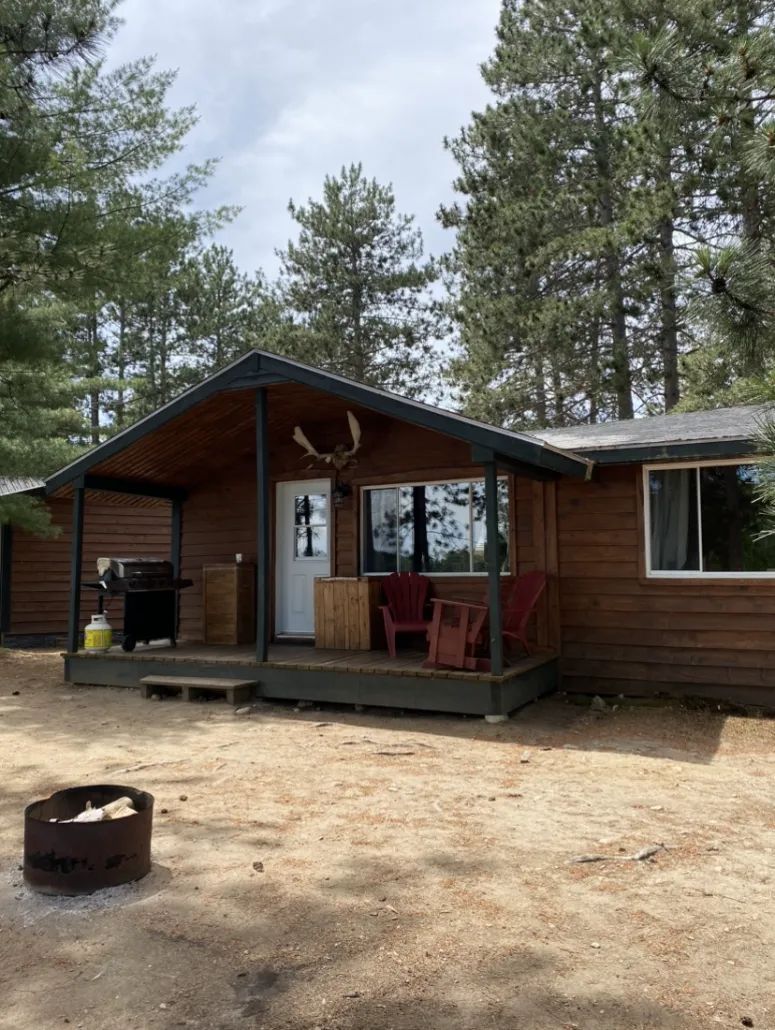 View of the exterior of cottage 4 with its deck, barbecue, and outdoor fire pit.