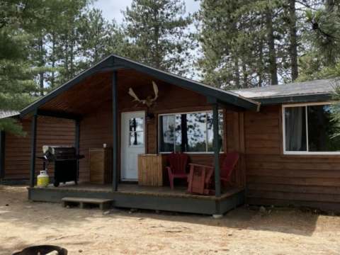View of the exterior of cottage 4 with its deck, barbecue, and outdoor fire pit.