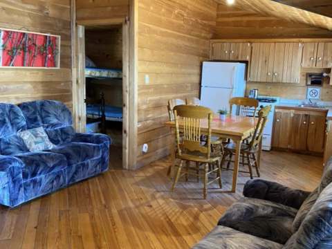 The chalet's open area includes a living space with two sofas, a dining table, and a kitchen.