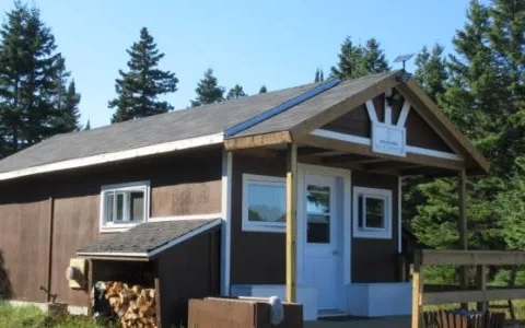 Exterior view of the hunting camp located in the forest with its wood storage area.