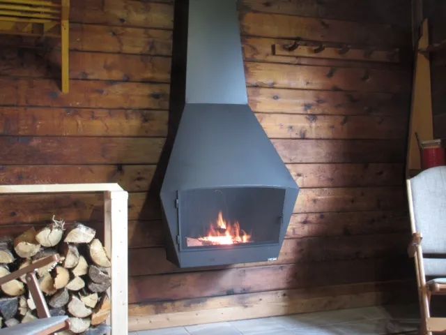 A modern suspended fireplace brings warmth and comfort to the wooden cottage living room.