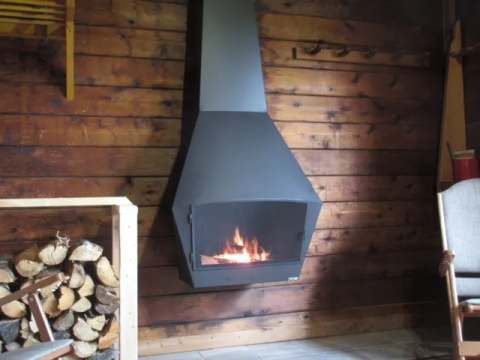 A modern suspended fireplace brings warmth and comfort to the wooden cottage living room.