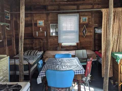 Vue intérieure du chalet rustique comprenant des lits, une table à manger et des murs en bois.