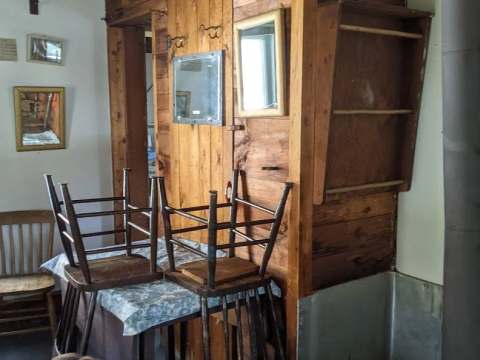 View of the cottage interior with table, wooden chairs and wood stove.