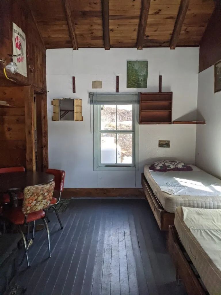 Interior view of the cabin featuring two single beds and a dining table with chairs.