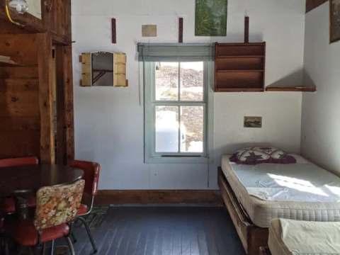 Vue intérieure du chalet comprenant deux lits simples et une table à manger avec chaises.