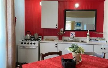The cottage's equipped kitchen features a stove, a sink, and a dining table.