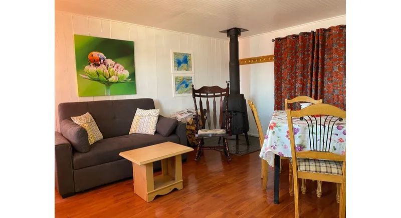 The cottage's living and dining area features a wood stove and comfortable furniture.