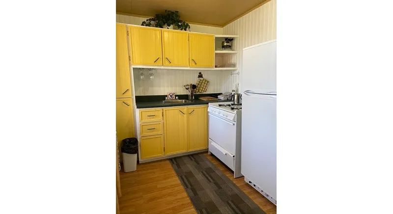 The cabin's equipped kitchen features yellow cabinets, a stove, and a refrigerator.