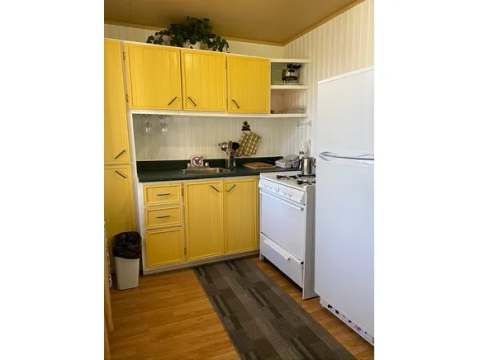 The cabin's equipped kitchen features yellow cabinets, a stove, and a refrigerator.