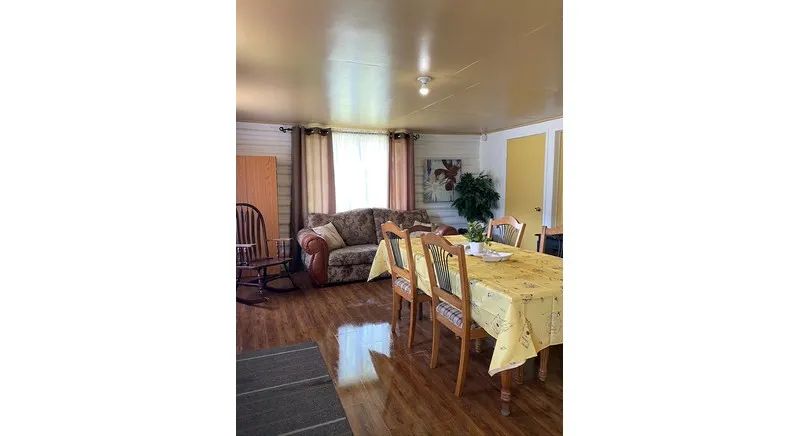 The open area of the cottage includes a dining table and a living area with a sofa and rocking chair.