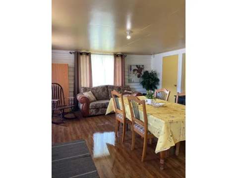 The open area of the cottage includes a dining table and a living area with a sofa and rocking chair.