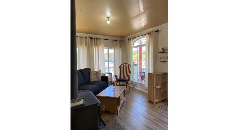 The cottage living room includes a sofa, a rocking chair, and a wood stove.