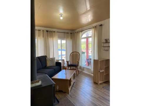 The cottage living room includes a sofa, a rocking chair, and a wood stove.