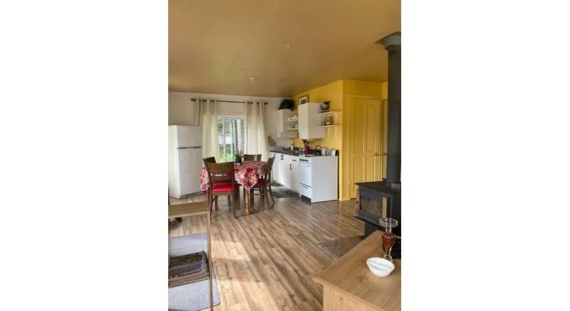 The cottage kitchen and dining area are equipped with a wood stove and household appliances.