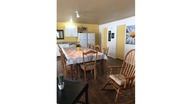 The cottage dining room features a large wooden table with chairs and a rocking chair.