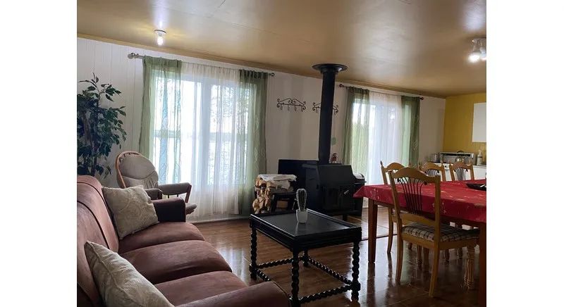 The open-plan cabin features a comfortable living area with a wood stove and a dining room.