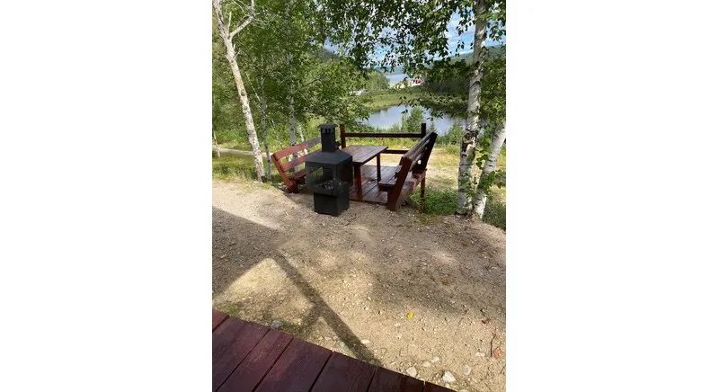 An outdoor relaxation area with a fire pit and a view of the lake in front of the cabin.