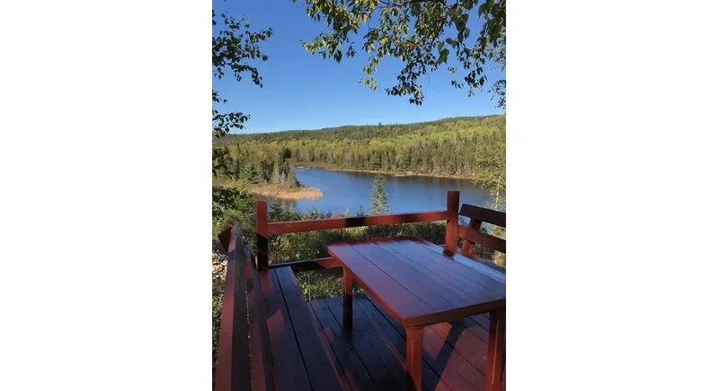 The cottage deck offers an open view of the lake and the surrounding forest.