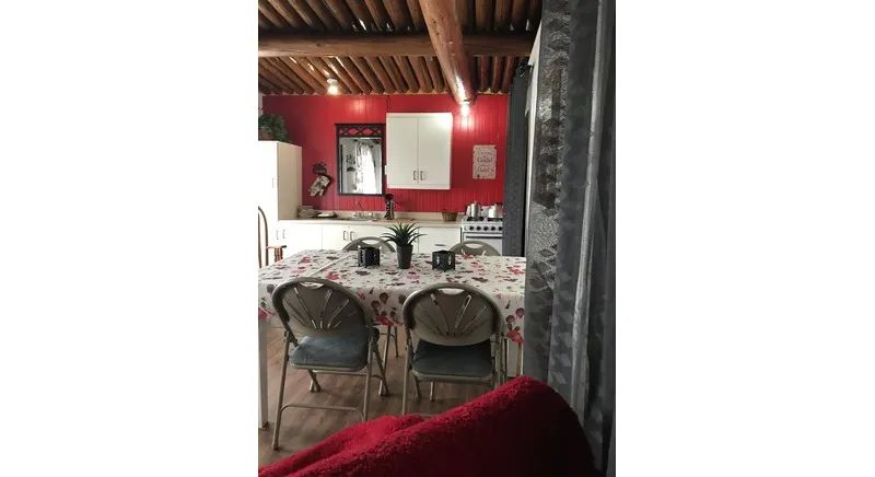 The dining area and functional kitchen of the cottage featuring a rustic wood ceiling.