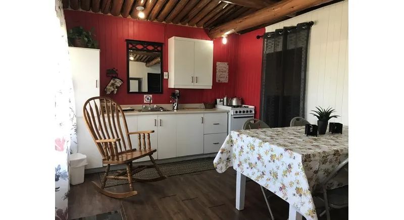 View of the cottage kitchen and dining area, equipped with a stove and a rocking chair.