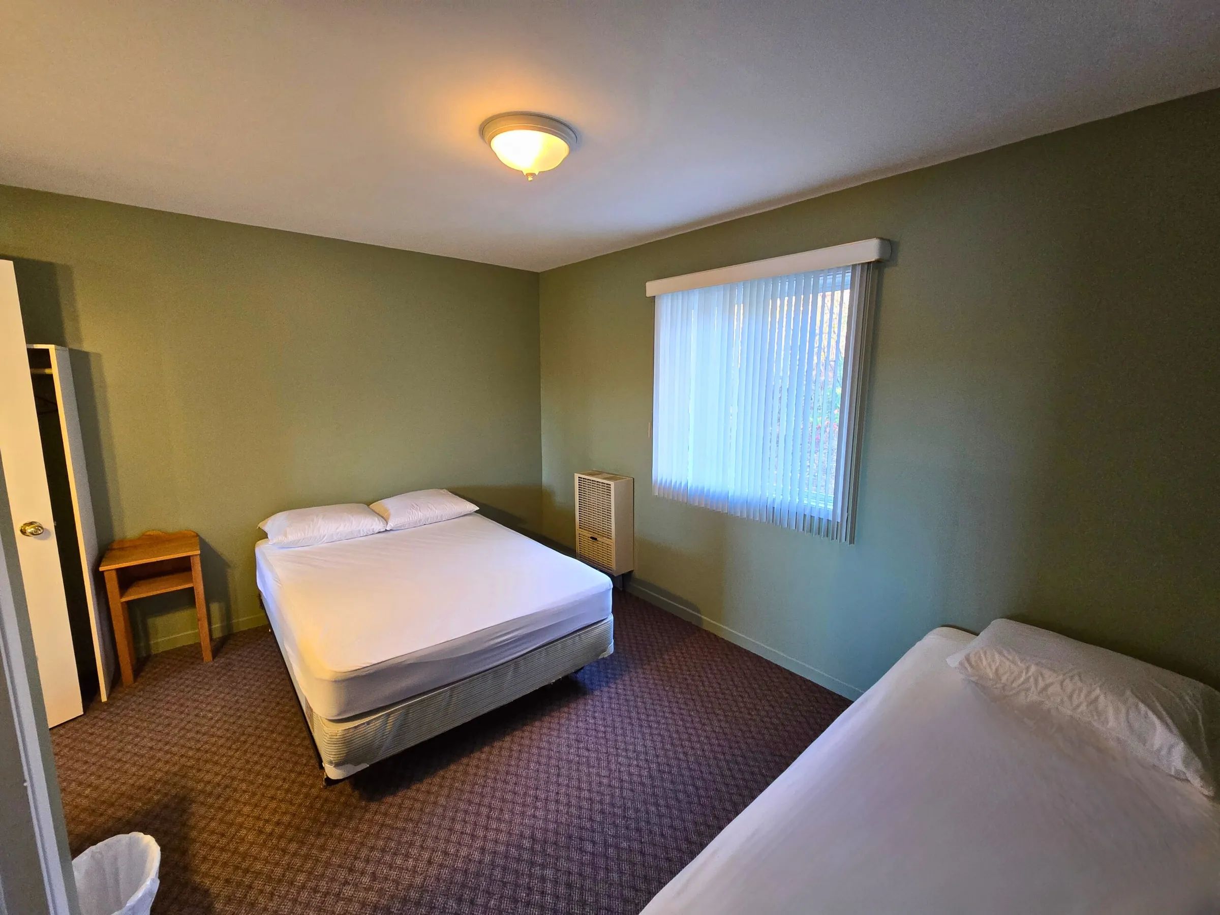 The studio bedroom features a queen bed, a single bed, and a wardrobe.