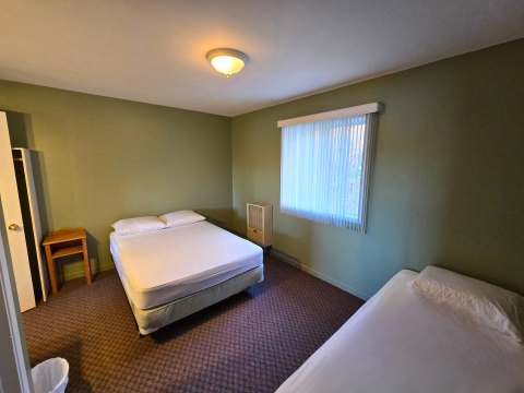 The studio bedroom features a queen bed, a single bed, and a wardrobe.