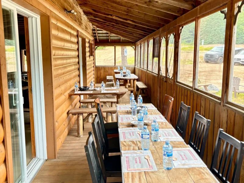 La véranda vitrée de l'auberge offre des tables disposées pour les repas en groupe.