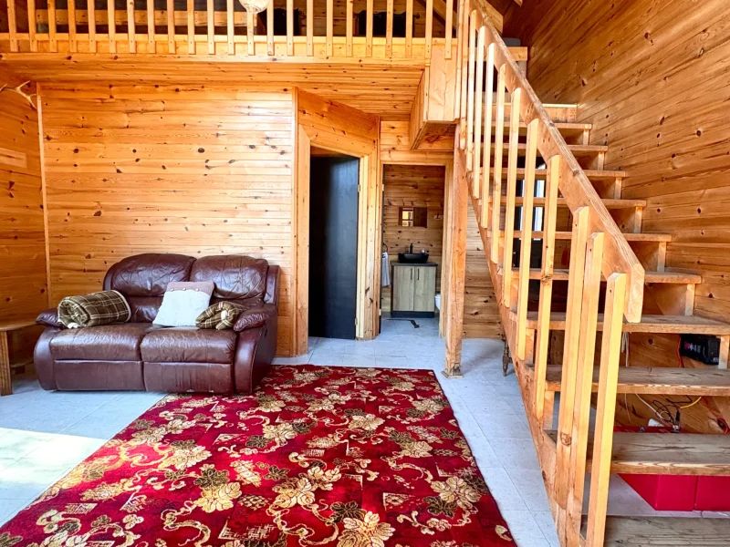 The Coucoucache cabin living area features a sofa and stairs leading to a mezzanine.