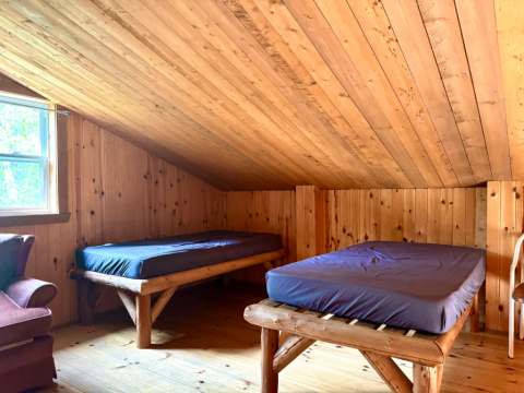 Chambre avec deux lits simples et plafond mansardé en bois au chalet Southerland.