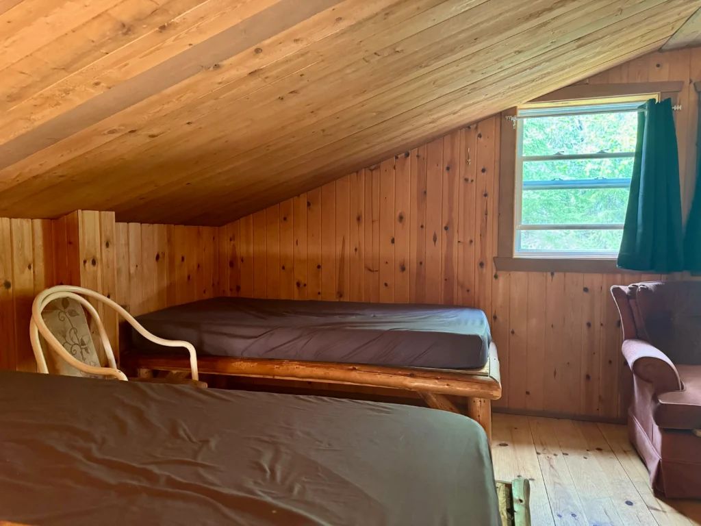 Cette chambre sous le toit du chalet Southerland comprend deux lits simples et un fauteuil.