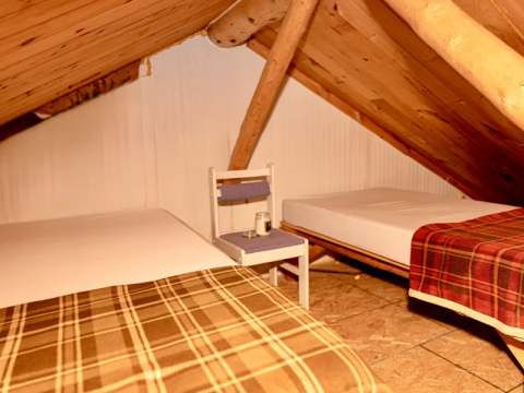Cette chambre mansardée comporte deux lits simples sous une structure en bois rustique.