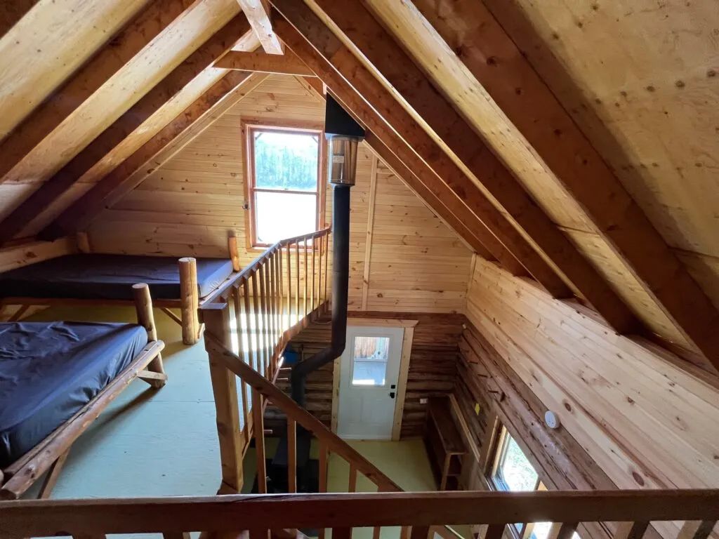 High-angle view of the mezzanine with beds and the wood stove of the Jolie cottage.