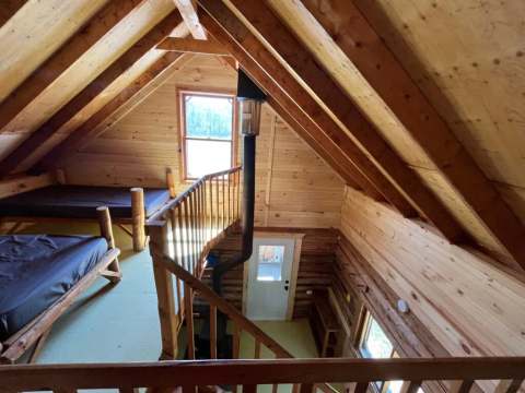 High-angle view of the mezzanine with beds and the wood stove of the Jolie cottage.