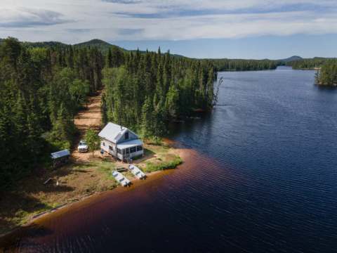 Aerial view of the Jolie cabin located by the lake with boats on the shore.