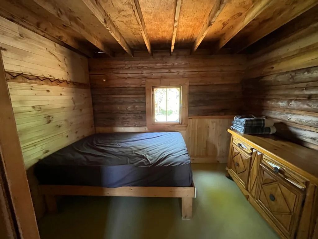 This rustic bedroom in Chalet Jolie features a comfortable bed and wooden furniture.
