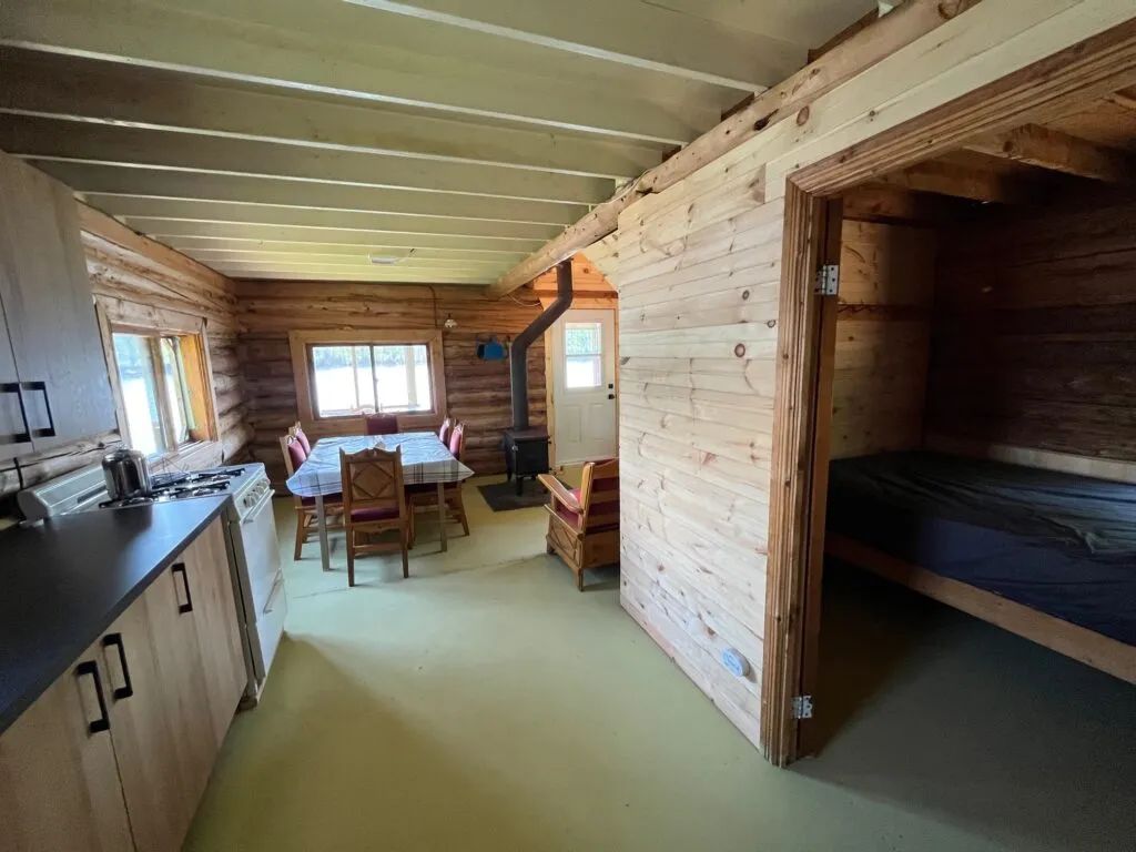 Overview of the cabin interior including the kitchen, dining area, and a bedroom.