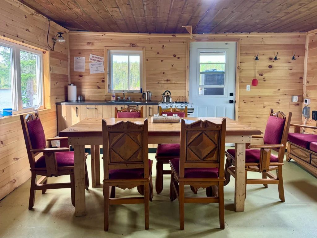 The cottage dining room features a wooden table and a functional kitchen area.