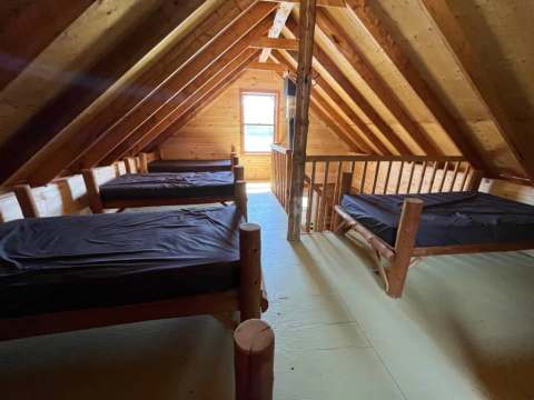 La mezzanine du chalet dispose de plusieurs lits simples sous le toit en bois.